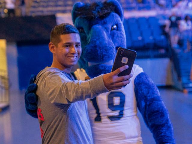 a student taking a selfie with Gunrock the mascot