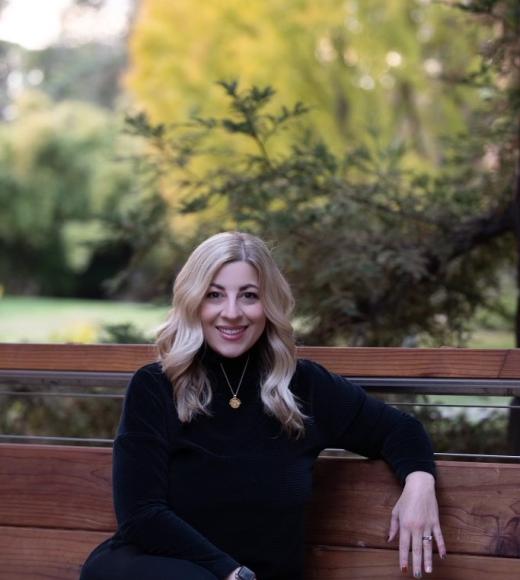 portrait of Executive Director of Communications Sallie Poggi sitting on a bench at UC Davis